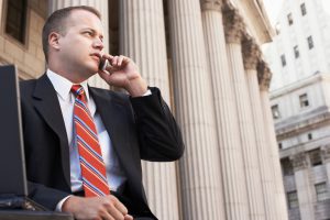 Businessman using mobile phone outside courthouse